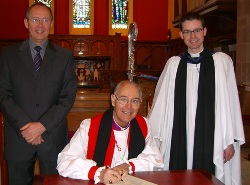 The Bishop signs the link with St Peter's Edinburgh, watched by Curate-Assistant the Rev Niall Sloane and the Chairman of the link sub-committee Brian Howe